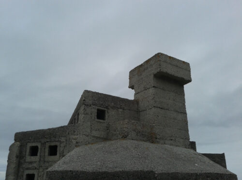 blocky concrete roof and chimney against grey sky