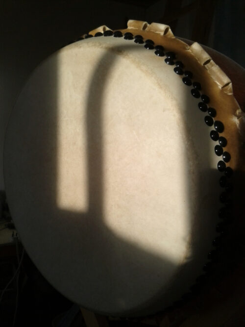 sun and shadow of window frame on stretched skin of vertically mounted taiko